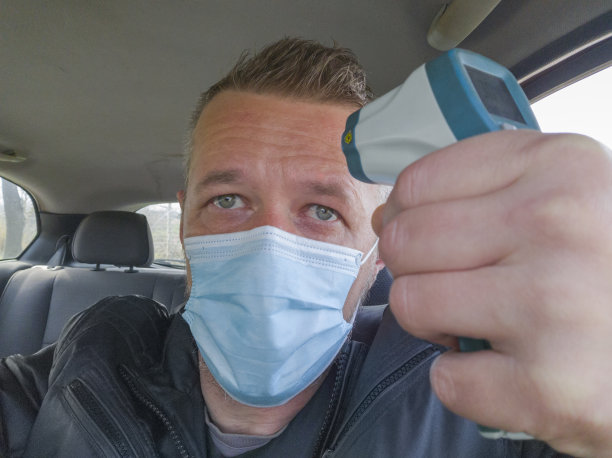 在新冠肺炎大流行期间用红外体温计测量汽车司机体温图片下载