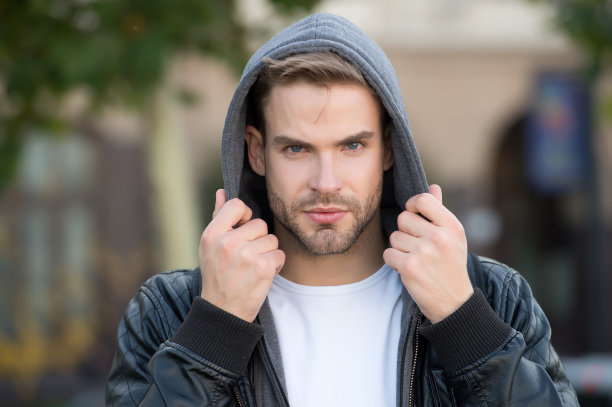 秋寒的时尚。英俊的男人穿连帽时装夹克。年轻人在户外秋天的风格。男装流行趋势与时令风格。秋季时尚衣橱图片下载