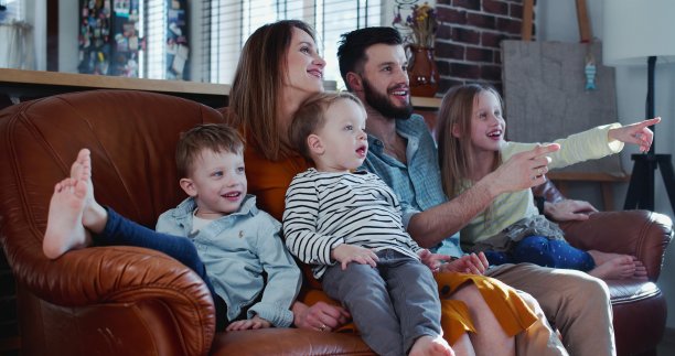 快乐的年轻白人家庭和三个可爱的孩子在沙发上观看电影图片下载