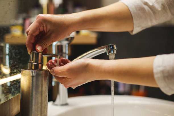 女人从瓶子里抽出肥皂，在浴室里洗手图片下载