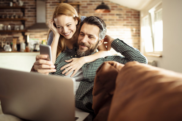 一对年轻夫妇在家里用手机图片下载