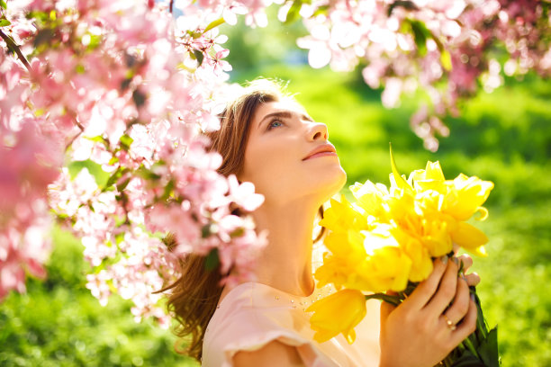 身穿漂亮春装手捧郁金香的年轻棕发女子图片下载