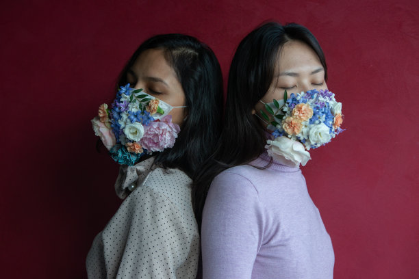 戴着带花防护口罩的女性，红色背景图片下载