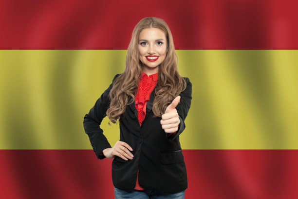 西班牙。快乐的女学生对着西班牙国旗竖起大拇指图片下载