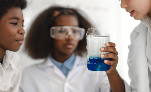 一组十几岁的学生在学校的实验桌上拿着试管学习做化学实验。教育的概念图片下载