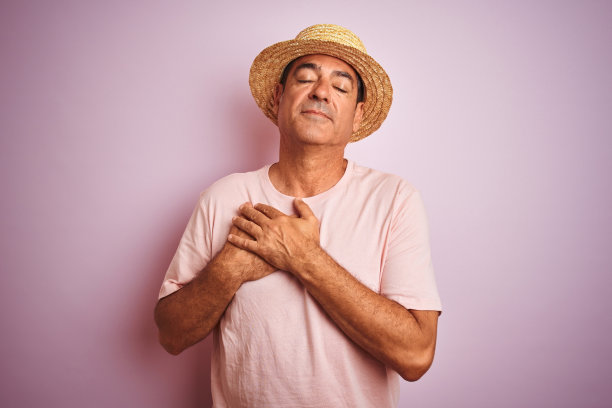 戴着夏帽的中年男人面带微笑，双手合十，闭着眼睛，心怀感激图片下载