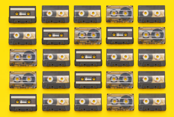 在彩色的黄色背景上排成一行的复古盒式磁带图片下载