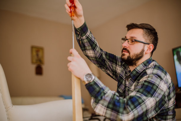 年轻男人修理客厅里的桌子素材图片