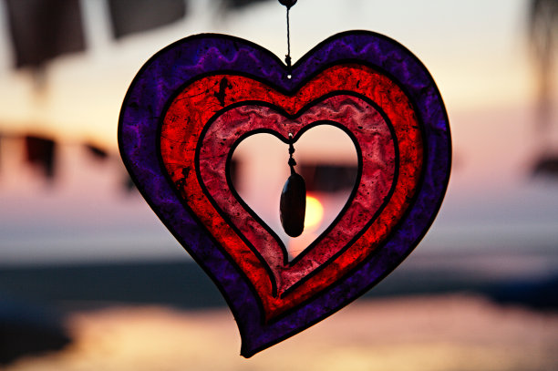 海上日落背景上的玻璃红心。浪漫的心跳。图片下载