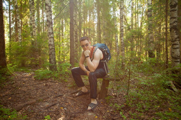 在春季森林的长椅上休息的英俊男人图片下载