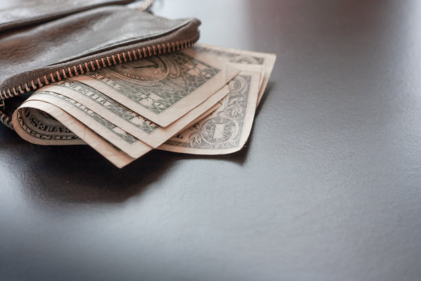 美元现金在皮革钱包上的黑色背景，钱的概念。一美元钞票。文本。储蓄，财富和贫穷。图片下载
