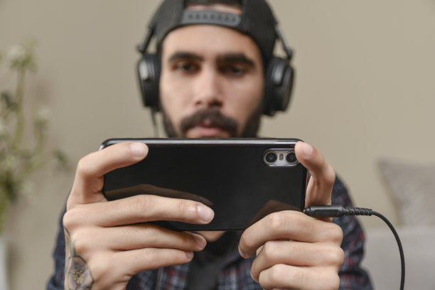 一个年轻人在家里玩手机游戏。智能手机游戏图片下载