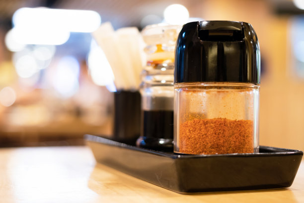 拉面餐厅餐桌上的日式餐具烧鱼酱、辣椒粉、牙签等包装为纸包的调味套装。图片下载