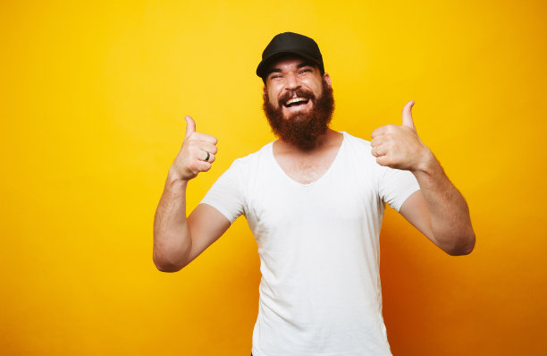 快乐的络腮胡男人在黄色背景上竖起大拇指图片下载