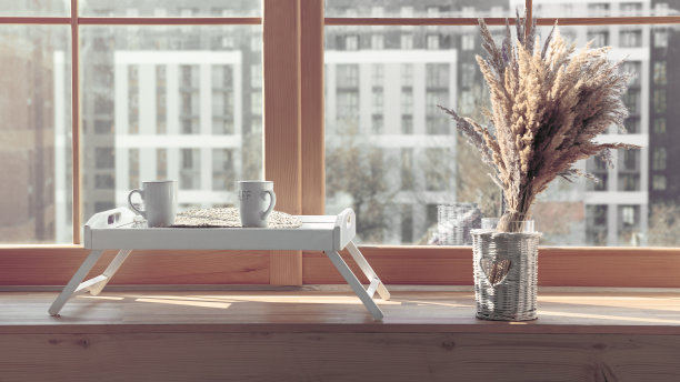 上菜桌上放着两只白色杯子，上面放着花，窗台上还有花瓶图片下载