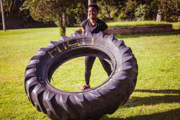 美丽的运动员女孩有一个举重训练和工作与一个大轮胎在公园股票照片图片下载