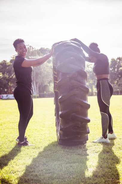 美丽的运动员女孩有一个举重训练和工作与一个大轮胎在公园库存照片图片下载