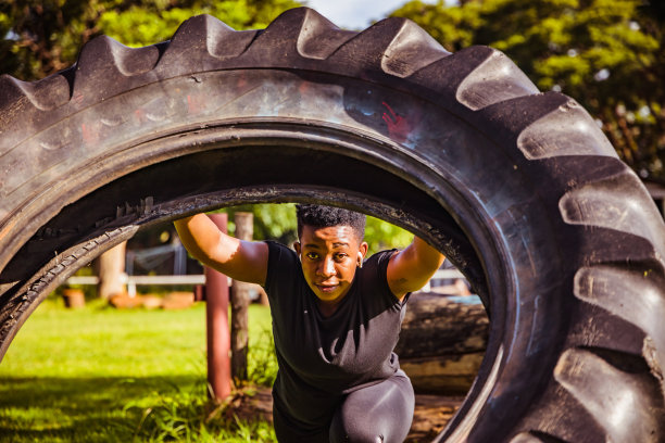 美丽的运动员女孩有一个举重训练和工作与一个大轮胎在公园股票照片图片下载