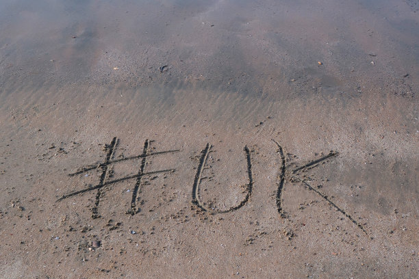 图片的标签标签写在阳光明媚的海滩上，英国单词写在沙滩上，Palolem海滩，印度果阿，概念社交媒体照片的手写在金色的沙子与现代标签前缀图片下载