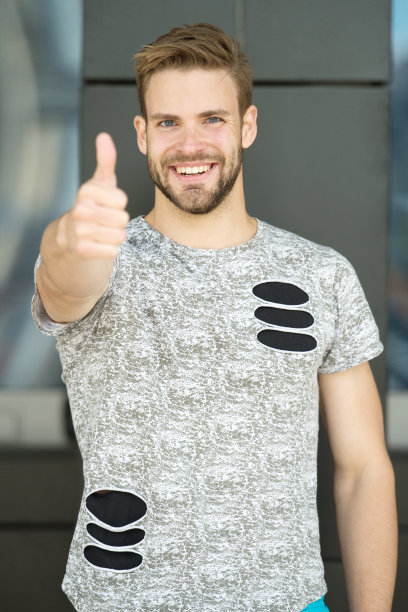 有胡子的男人或没刮胡子、穿着时髦衬衫的男人翘起大拇指。穿着时尚衬衫的男人脸上带着胡须，城市背景。时尚的概念。模特穿着时髦时髦的衣服图片下载