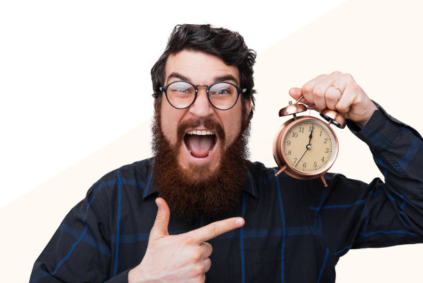 惊奇的大胡子嬉皮士在休闲指着闹钟图片下载