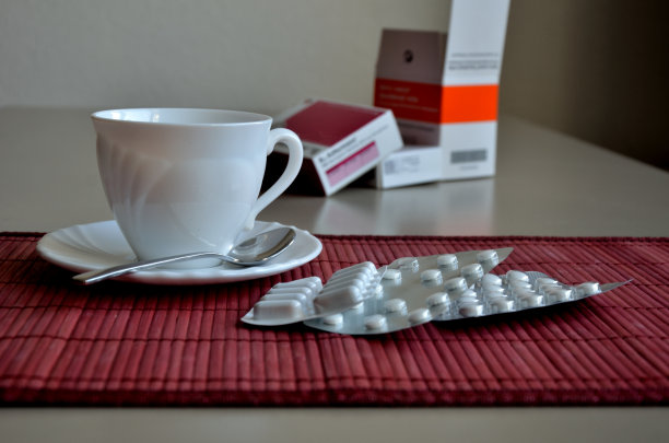 白色的咖啡杯，红色的垫子上有药泡图片下载