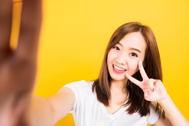 亚洲快乐肖像美丽可爱的年轻女子少女微笑站着穿t恤自拍照片，视频通话在智能手机上看起来孤立的摄像头图片下载