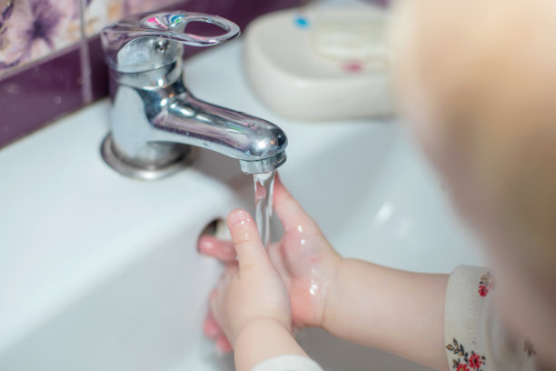 孩子把双手放在水龙头流出的水流下。节约用水。清洁手，阻止Covid-19、冠状病毒大流行的传播图片下载