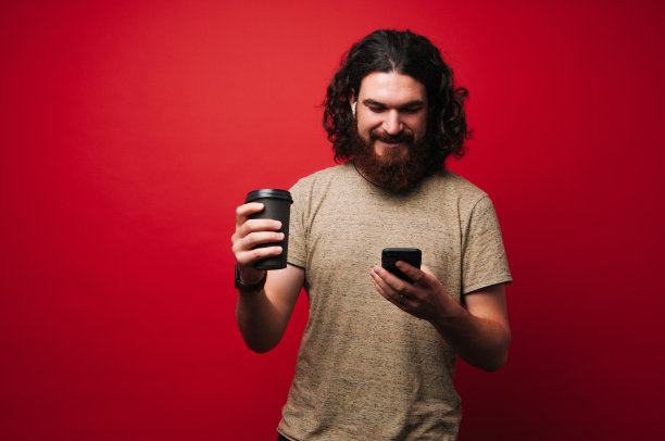 用手机和拿着咖啡或茶的长卷发的潮人肖像图片下载