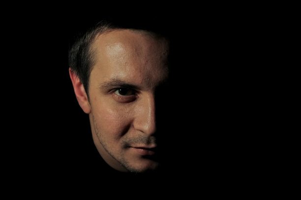 一个穿着黑色钥匙的年轻人的肖像。黑色背景上那家伙的肖像。人的情感的概念。图片下载