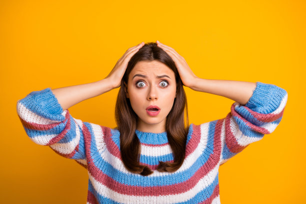 迷人的漂亮女士的特写照片张开嘴听可怕的可怕的坏消息不公平的情况金色的手臂在头上穿休闲条纹毛衣孤立的黄色背景图片下载