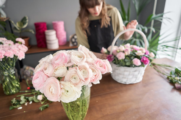 前景花瓶里的金凤花。花店概念。花匠在柳条篮子里制作插花。一束美丽的混合鲜花。花交付。图片下载