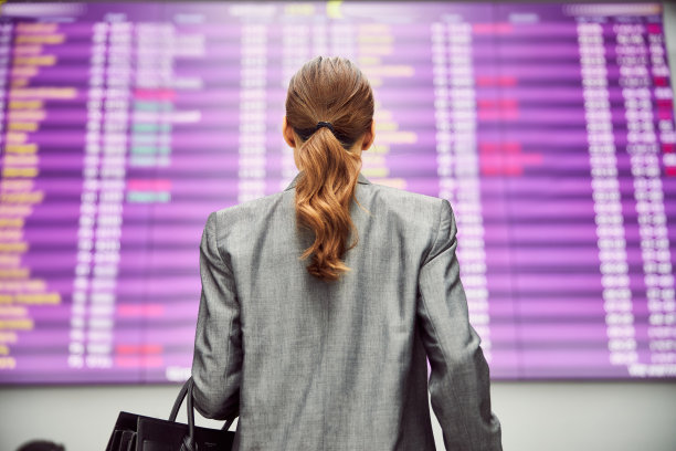 年轻女子在机场看航班信息显示屏图片下载