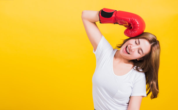 肖像亚洲泰国美丽的年轻女子站在微笑在红色拳击手套拳头和闭上眼睛，拍摄照片在摄影棚拍摄孤立的黄色背景图片下载