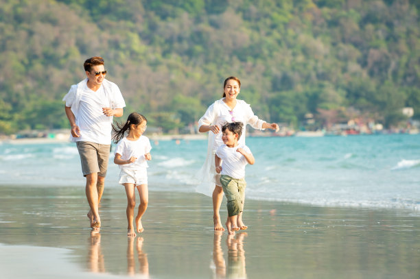 在夏日海滩上奔跑玩耍的幸福亚洲家庭图片下载