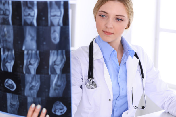 一位女医生在医院窗户附近检查x光照片。在工作中的外科医生或整形外科医生医疗保健理念。蓝色的治疗师衬衫看起来不错图片下载