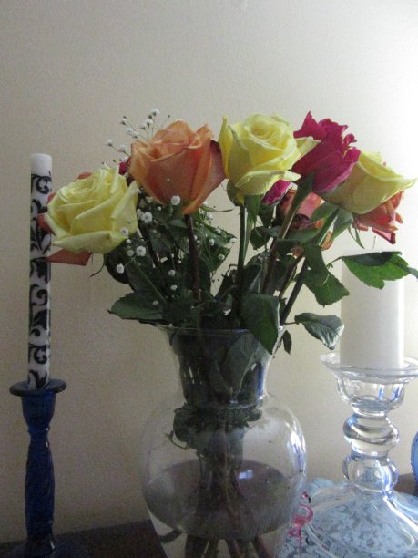 蜡烛旁花瓶里的彩色玫瑰图片下载