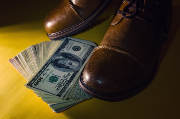 概念照片的棕色皮革男鞋，与美元内的鞋子上的黄色背景在黑暗与灯光图片下载