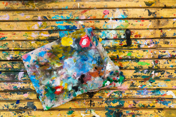 一块染有彩色油漆色背景的布料。一块白色的布用各种颜色的颜料刷涂在木板桌上纹理图片下载