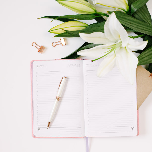 美丽新鲜的白色百合和笔记本与空白页在白色的背景。心情写博客的概念。广场照片图片下载