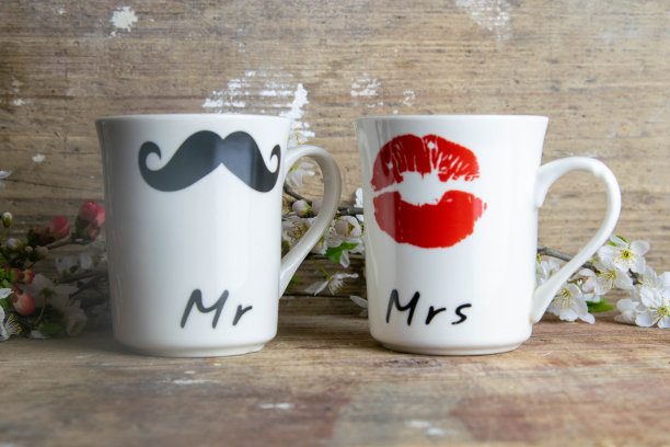 木桌上一起放着男人和女人的脸和心的两杯咖啡。情人节快乐的概念图片下载