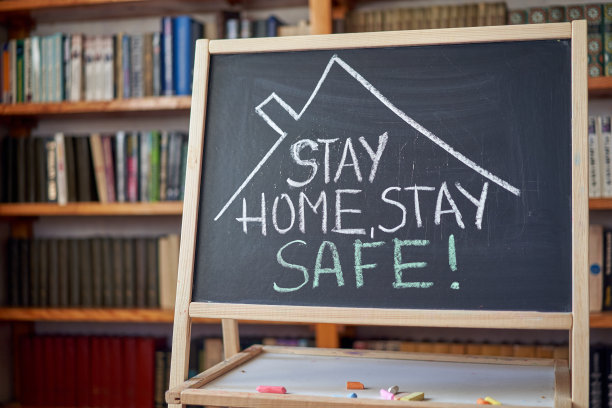 题词留在家里。爆发的警告。用白色粉笔在黑板上写下与全球冠状病毒疫情相关的内容。图片下载