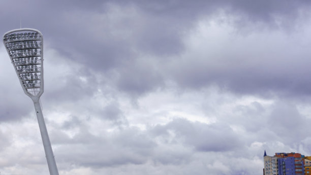 桅杆与聚光灯照亮体育场在戏剧性的天空背景。图片下载