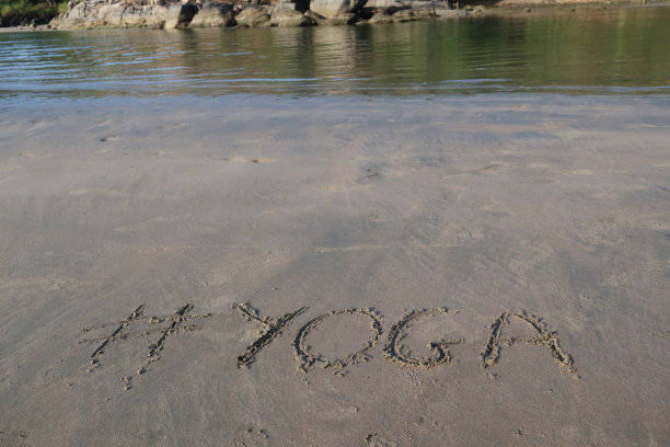 图片的标签标签写在阳光明媚的海滩上，瑜伽的单词写在海边的沙子，帕洛伦海滩，印度果阿，概念社交媒体照片的手写在金色的沙子与现代标签前缀图片下载