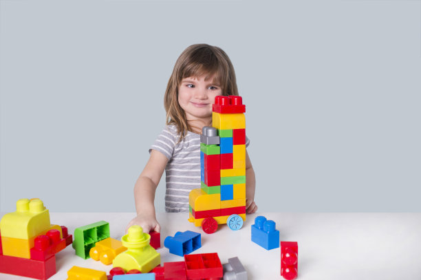 小女孩在室内玩着许多五颜六色的塑料积木。图片下载