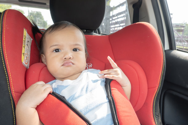 亚洲女婴正确地坐在红色汽车安全座椅上图片下载