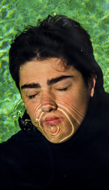 穿着黑帽衫的年轻人站在浴室里。图片下载