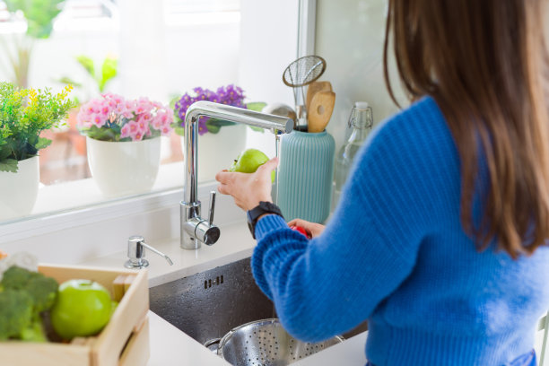 年轻女子用水槽里的水清洗蔬菜和水果素材图片