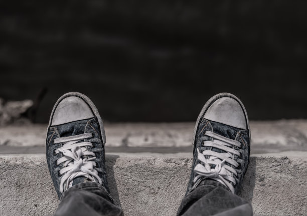 一个年轻人的腿站在河边，黑白色调，抑郁的概念。图片下载