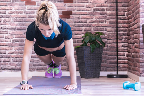 金发女孩在家在沙龙里做运动。只是因为它能抵御新型冠状病毒他穿着运动服，准备做一个俯卧撑。图片下载